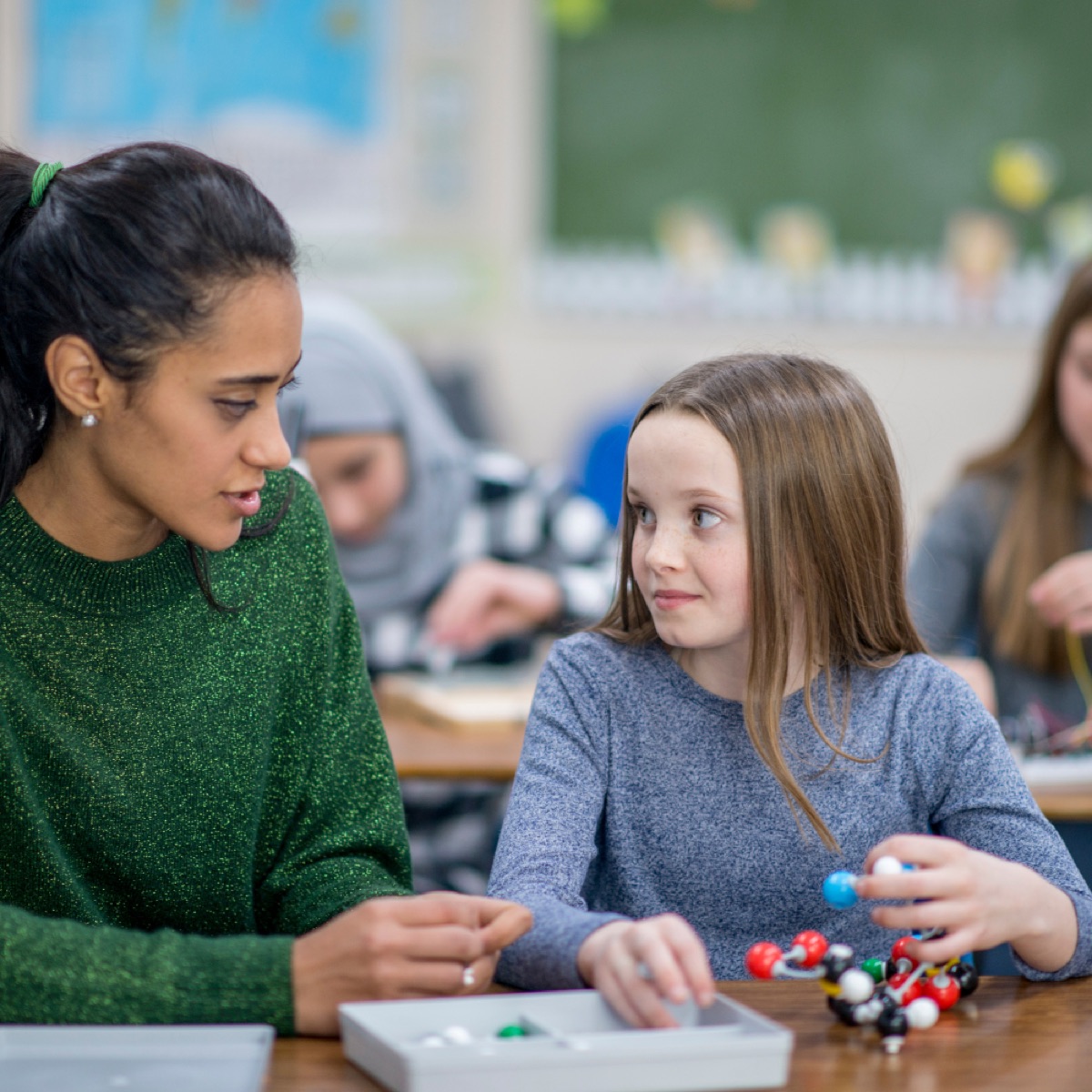 Lehrerin unterstützt eine Schülerin im Unterricht